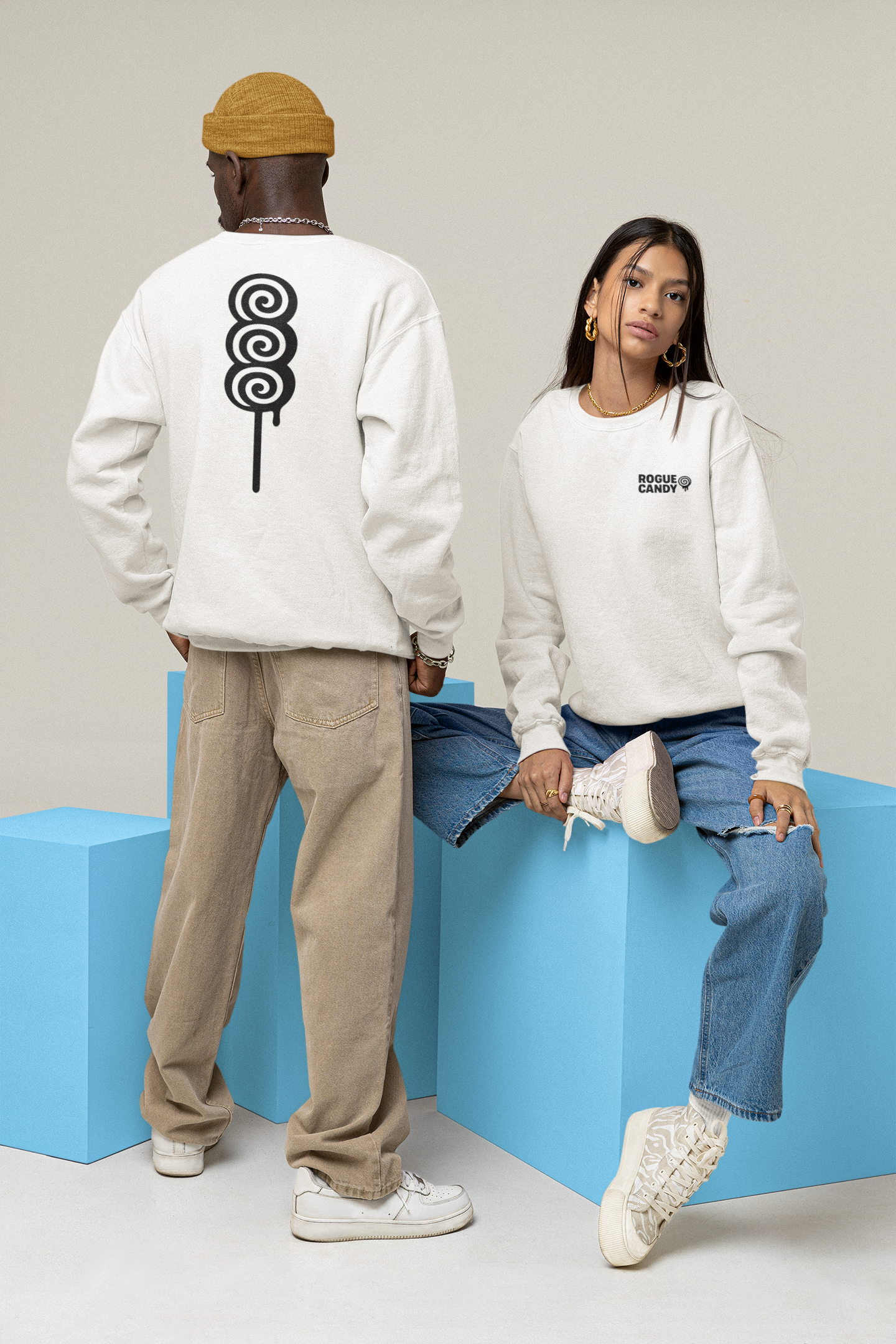 Two people wearing white sweatshirts with unique designs sitting on blue blocks against a light gray background.