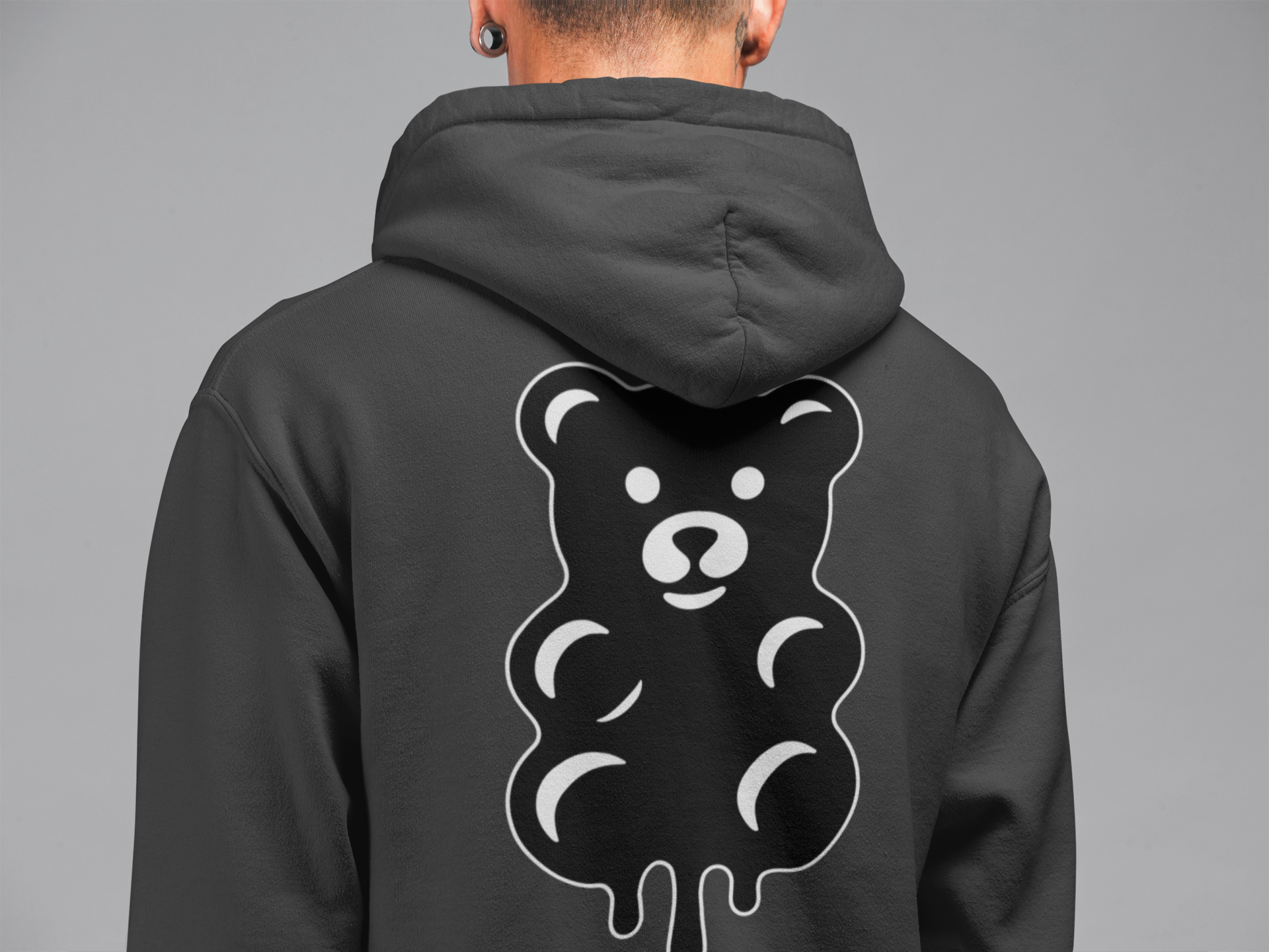 Person wearing a black hoodie with a bear graphic on the back against a gray background