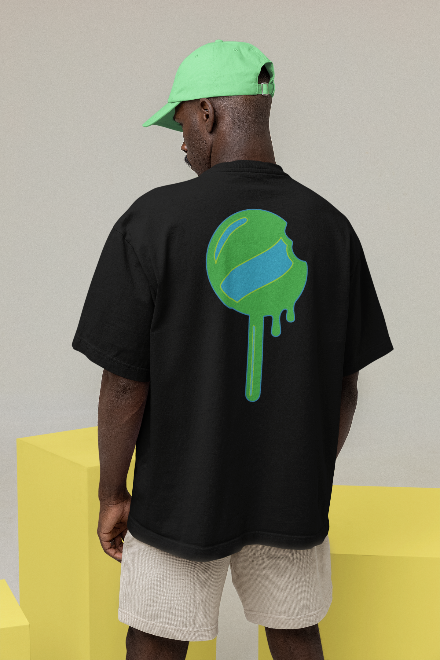 Person wearing a black t-shirt with a green and blue graphic on the back, standing against a plain background.