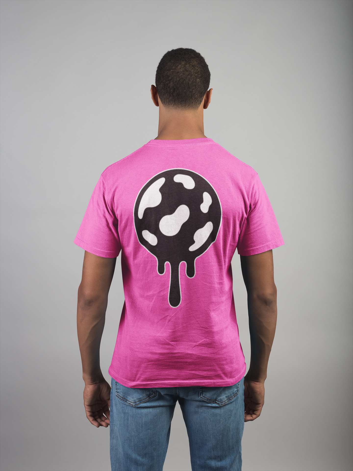 Person wearing a neon pink t-shirt with a black and white jaw breaker design on the back against a gray background
