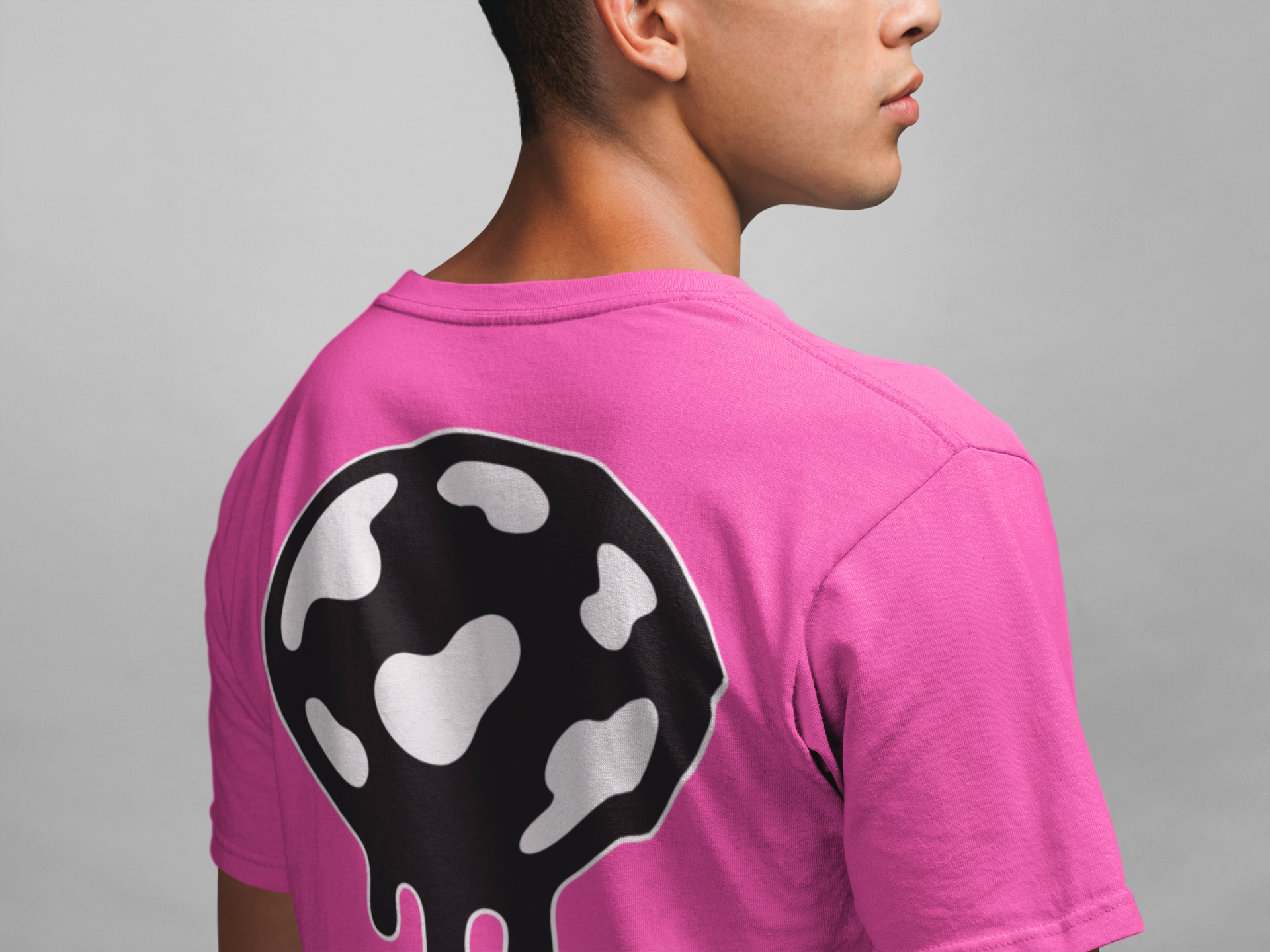 Person wearing a neon pink t-shirt with a black and white jaw breaker design on the back against a gray background