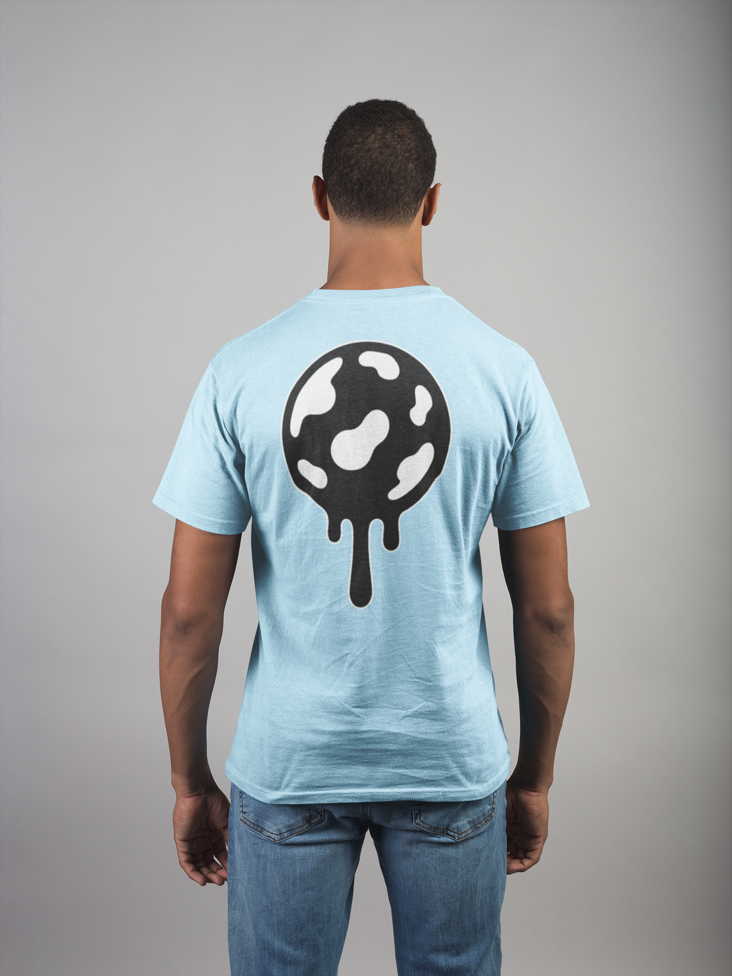 Person wearing a light blue t-shirt with a black and white jaw breaker design on the back, standing against a gray background.