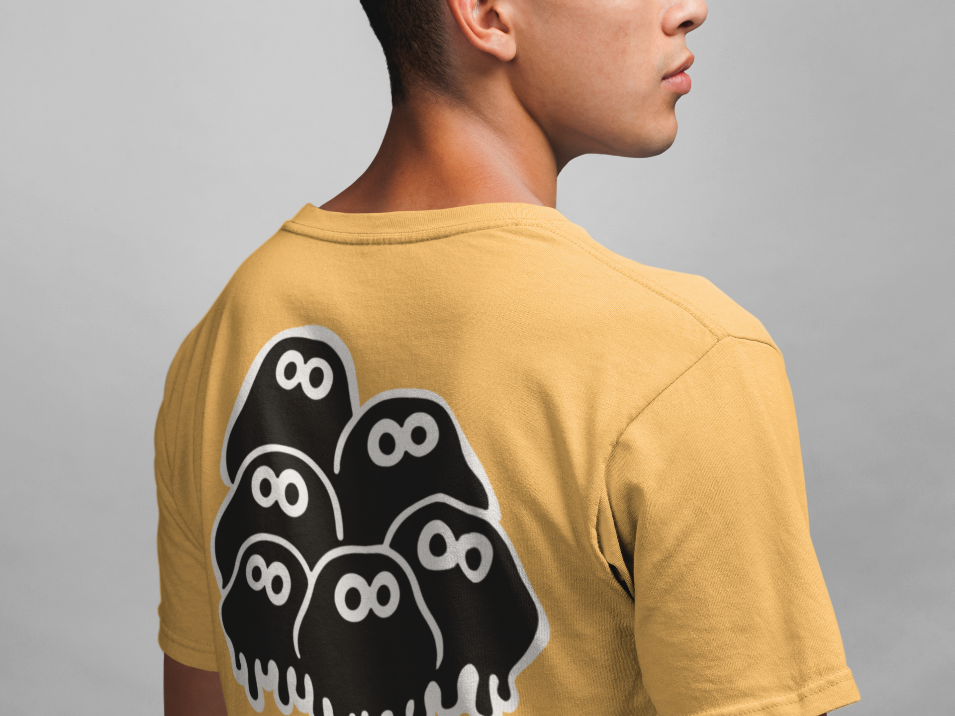 Person wearing a mustard yellow t-shirt with black graphic geek clusters design on the back against a gray background