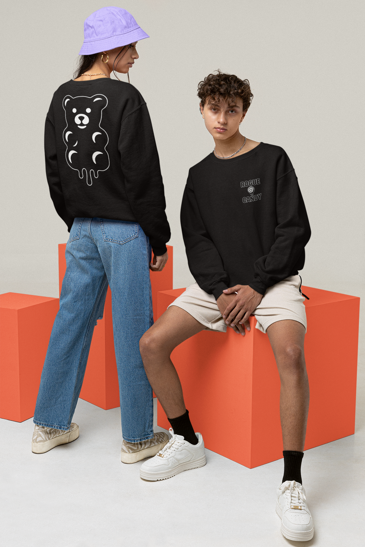 Two people wearing black sweatshirts with unique designs on a plain background