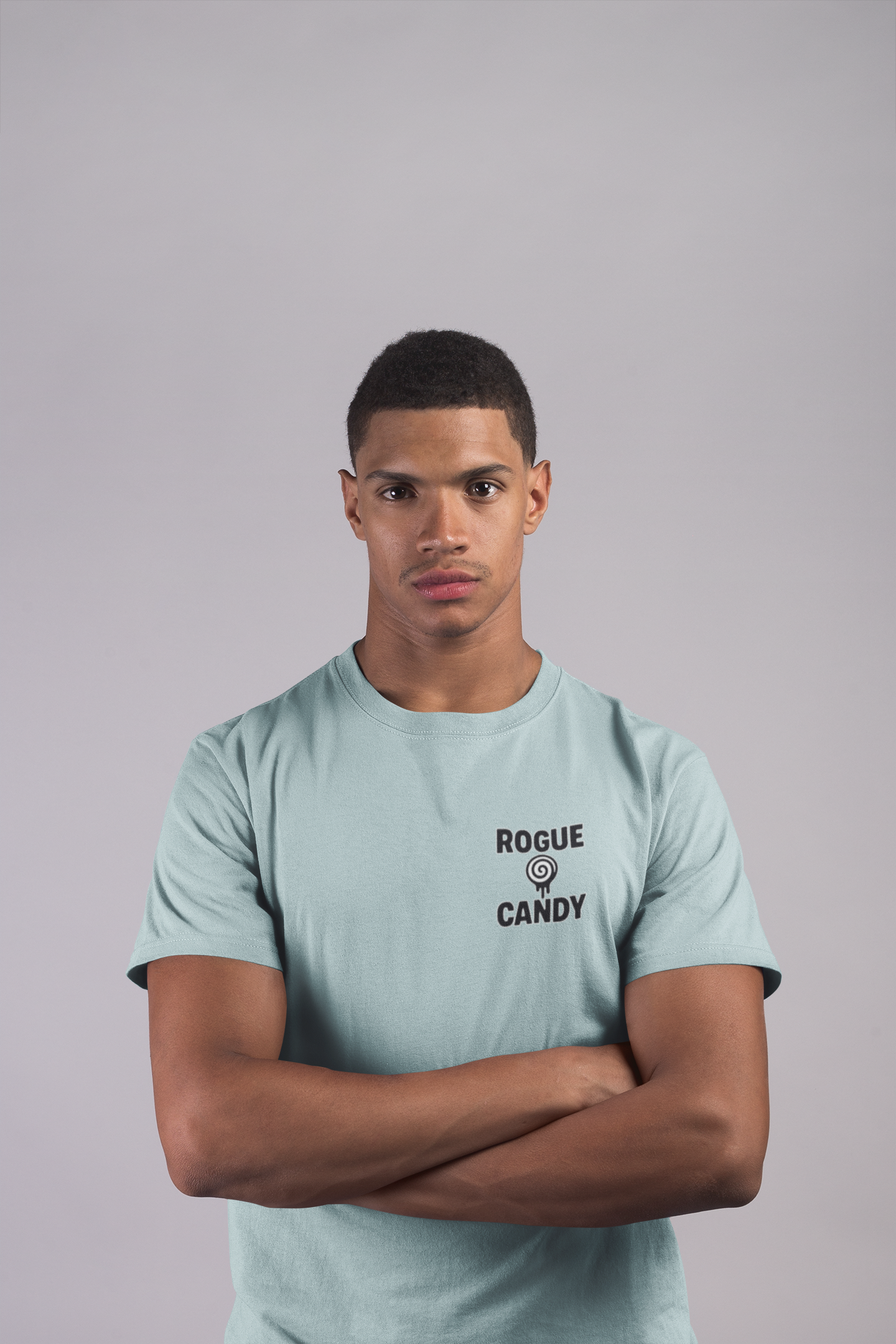 Man wearing a light teal t-shirt with Rogue Candy text logo on chest,  on a gray background
