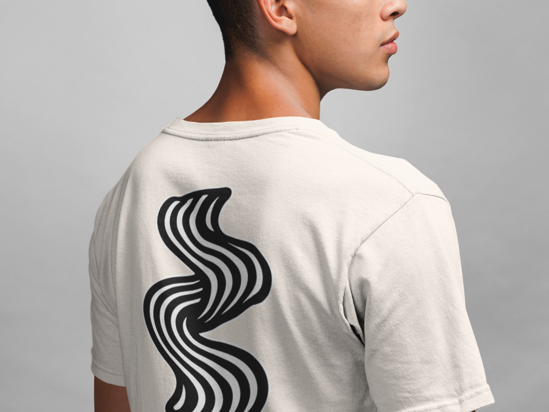 Person wearing a off white t-shirt with a black wavy design on the back against a gray background