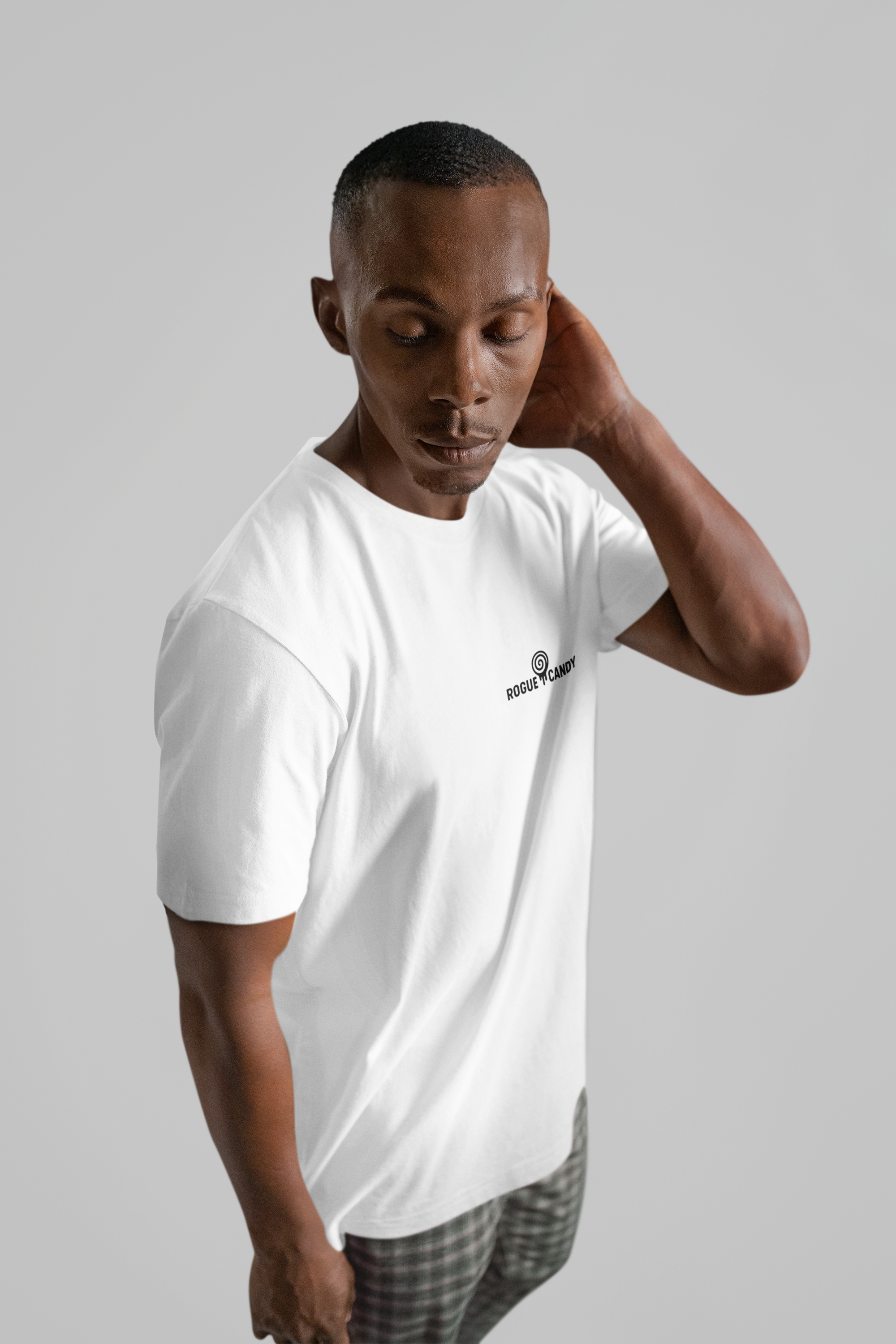 Man wearing white t-shirt with rogue candy logo print small on chest, on grey background