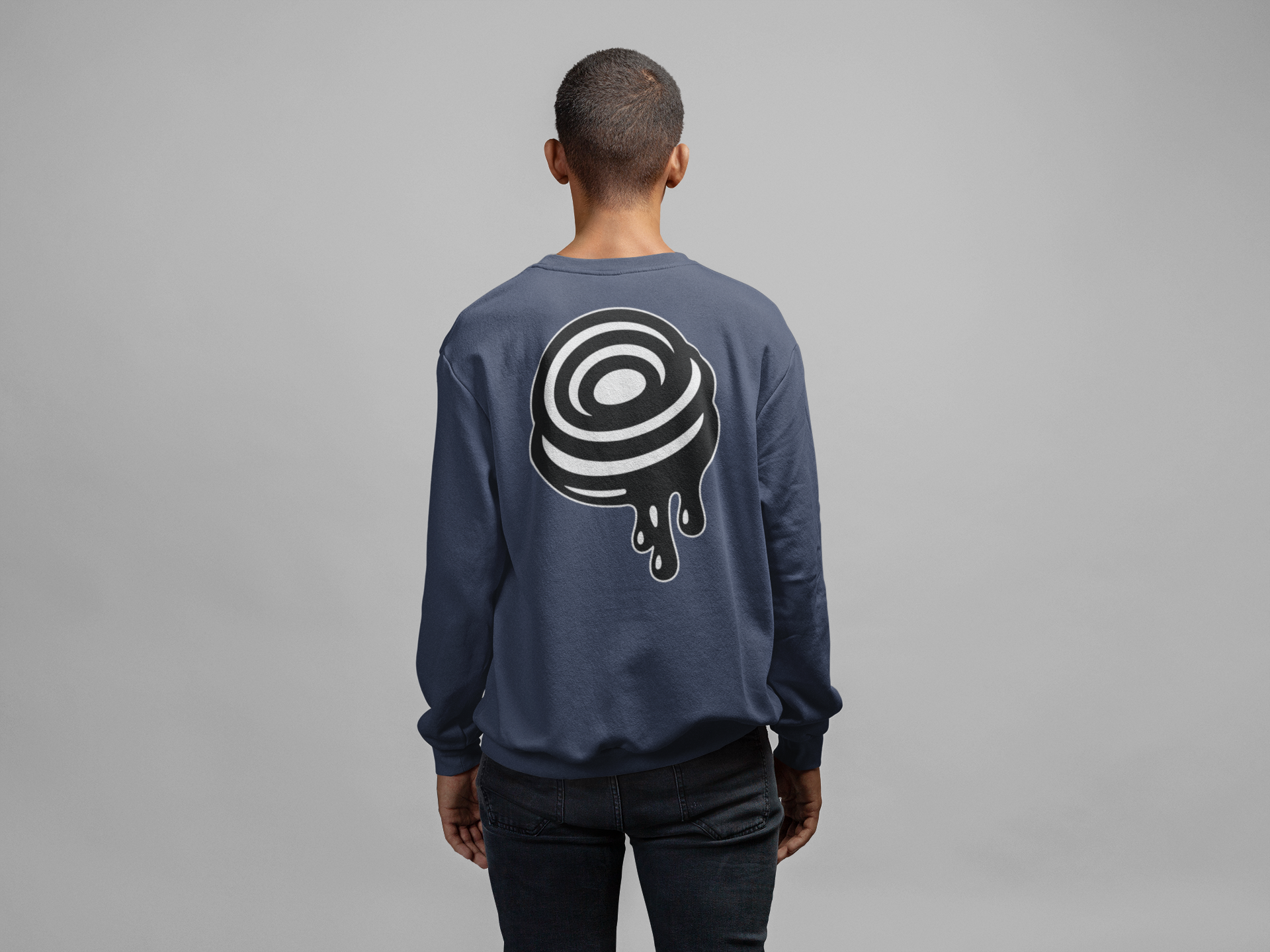 Person wearing a navy blue sweatshirt with a black and white design on the back against a gray background