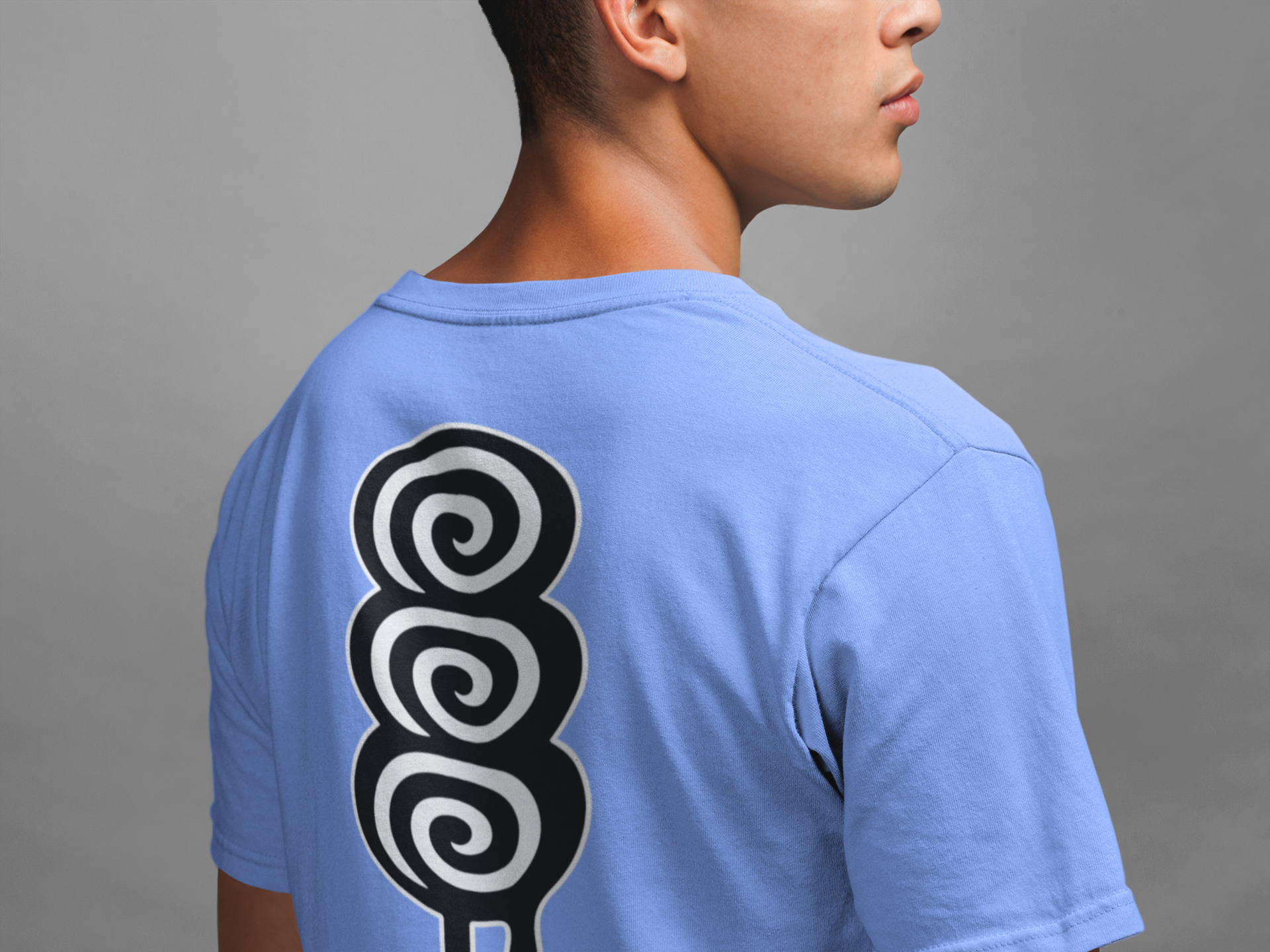 Person wearing a light blue t-shirt with a black and white spiral design on the back against a gray background